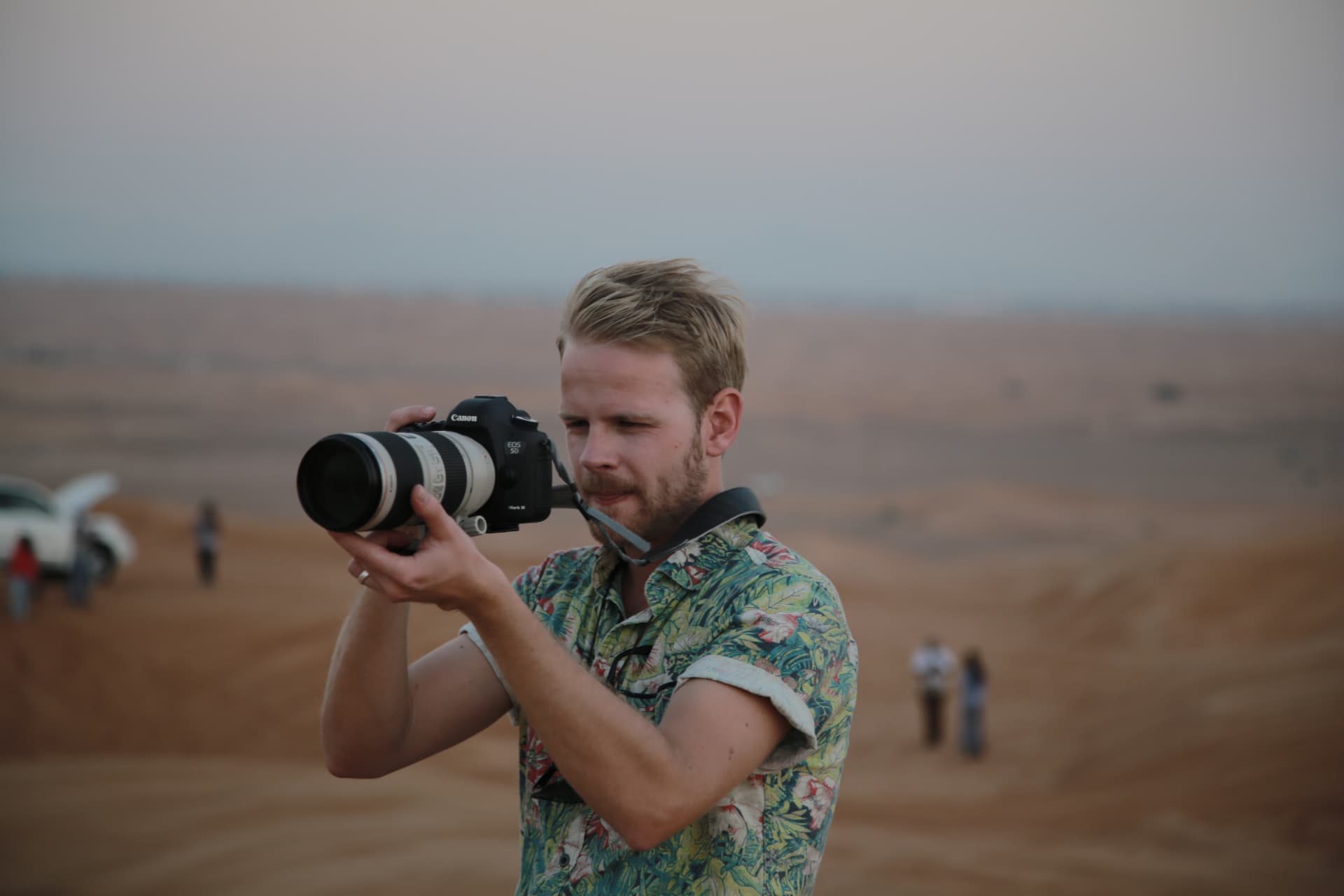 Eric filming with a camera in the desert at dusk